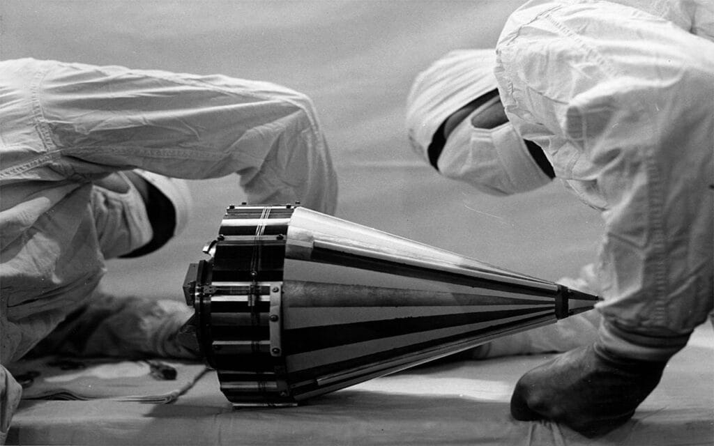 Looking more like surgeons, these technicians wearing "cleanroom" attire inspect the Pioneer III probe before shipping it to Cape Canaveral, Florida.