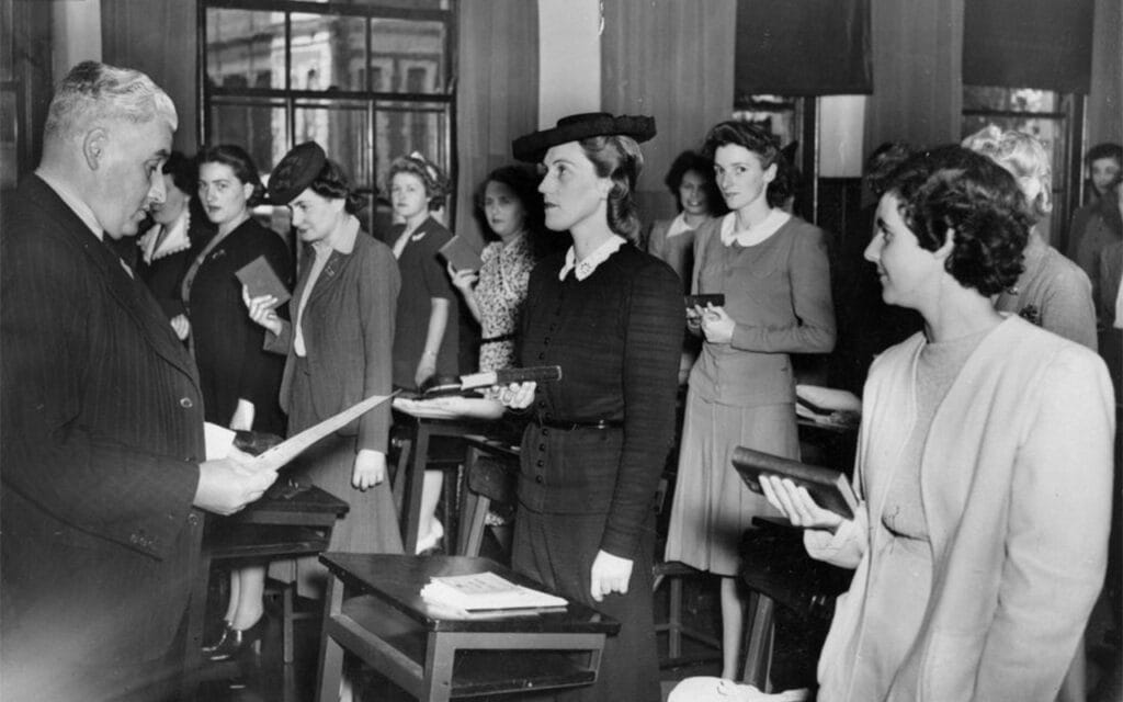 A man in a suit standing before a number of women holding bibles.