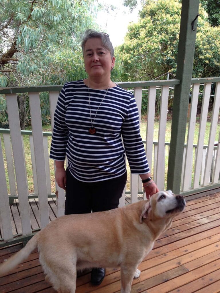 A woman wearing a striped t-shirt standing with a dog.