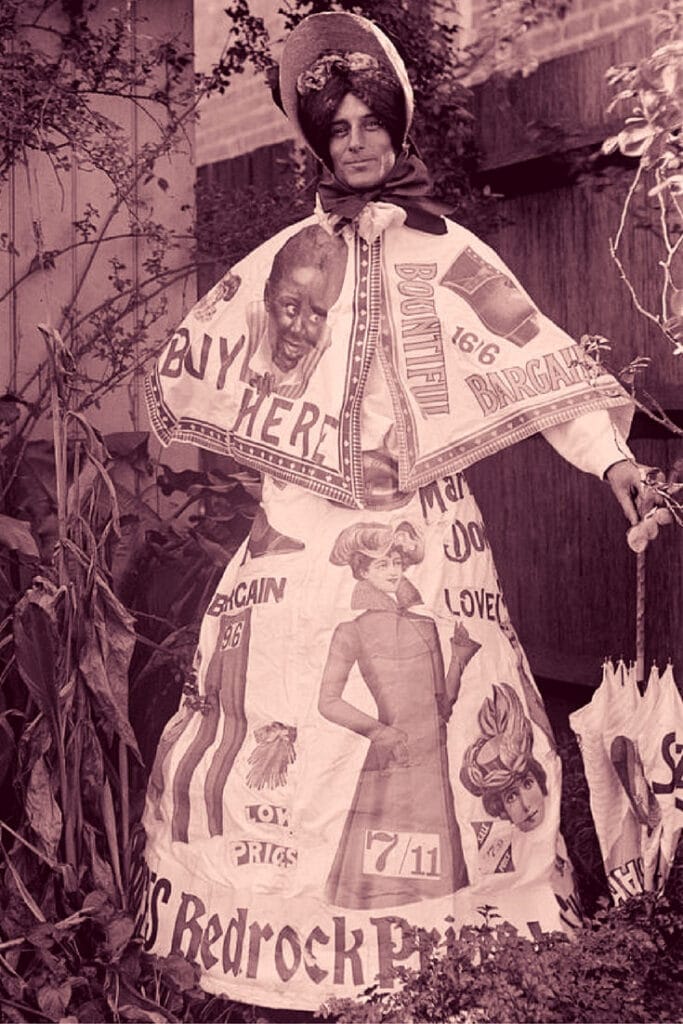 Full-length portrait of a man wearing a dress, possibly fancy dress, with advertisements on it.