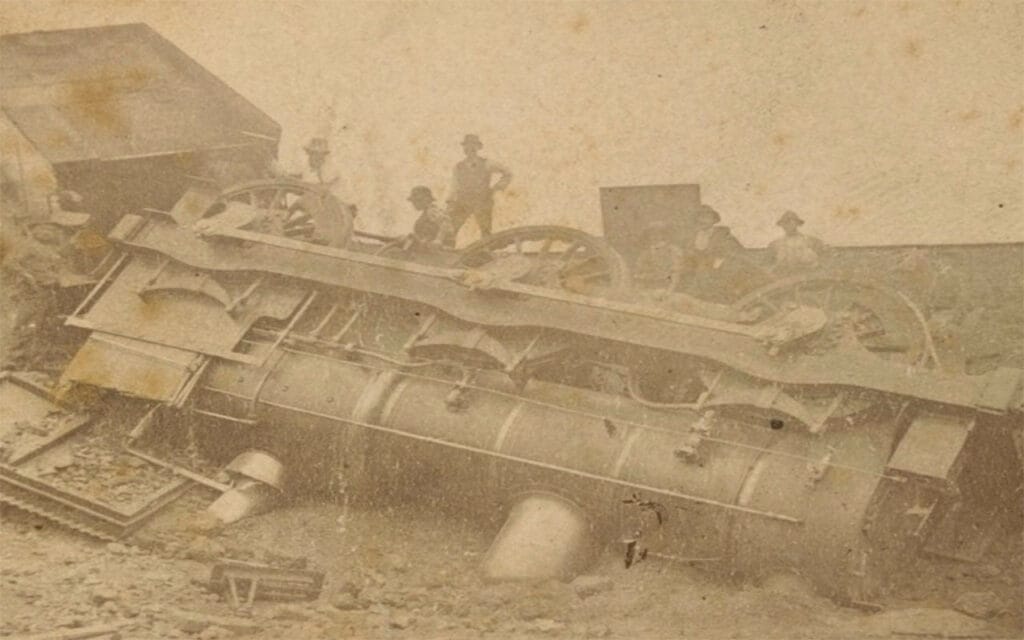 men standing around a derailed locomotive