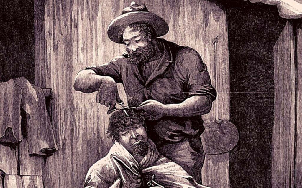 A man sitting on a box getting his hair cut.