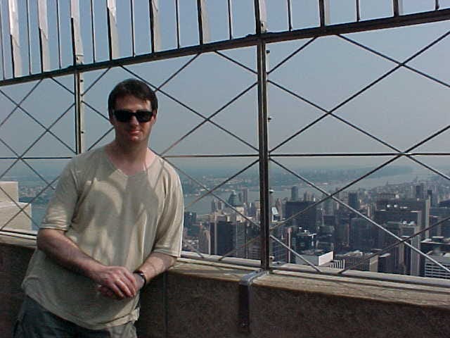 A man leaning on a fence at the Empire State Building in New York
