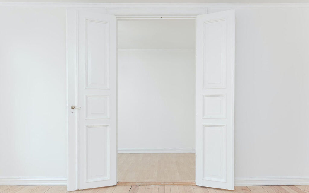 A white door set into a white wall.