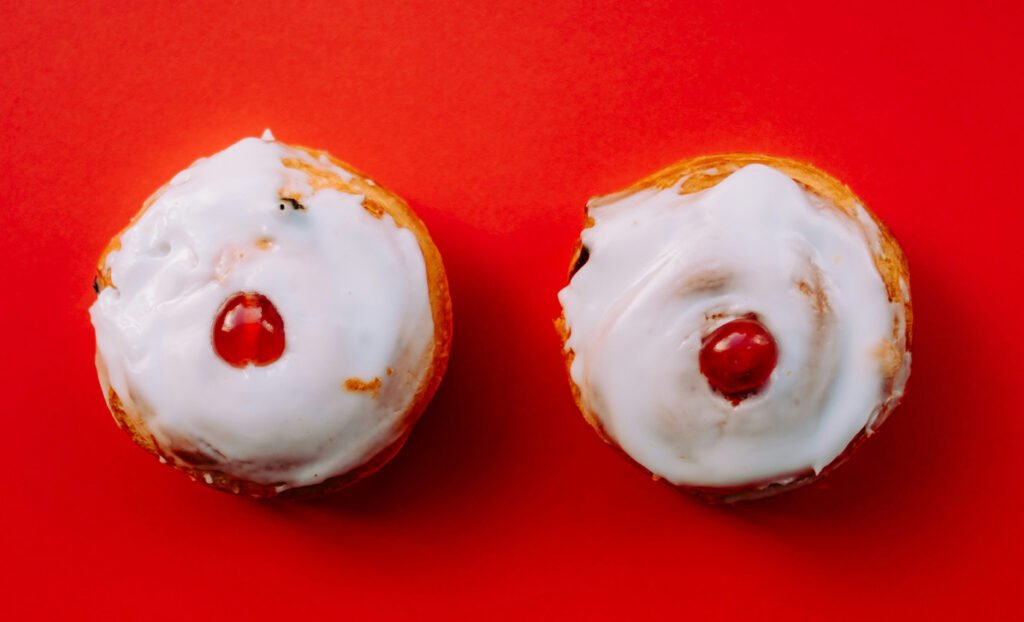 Two iced cupcakes with glace cherries on top