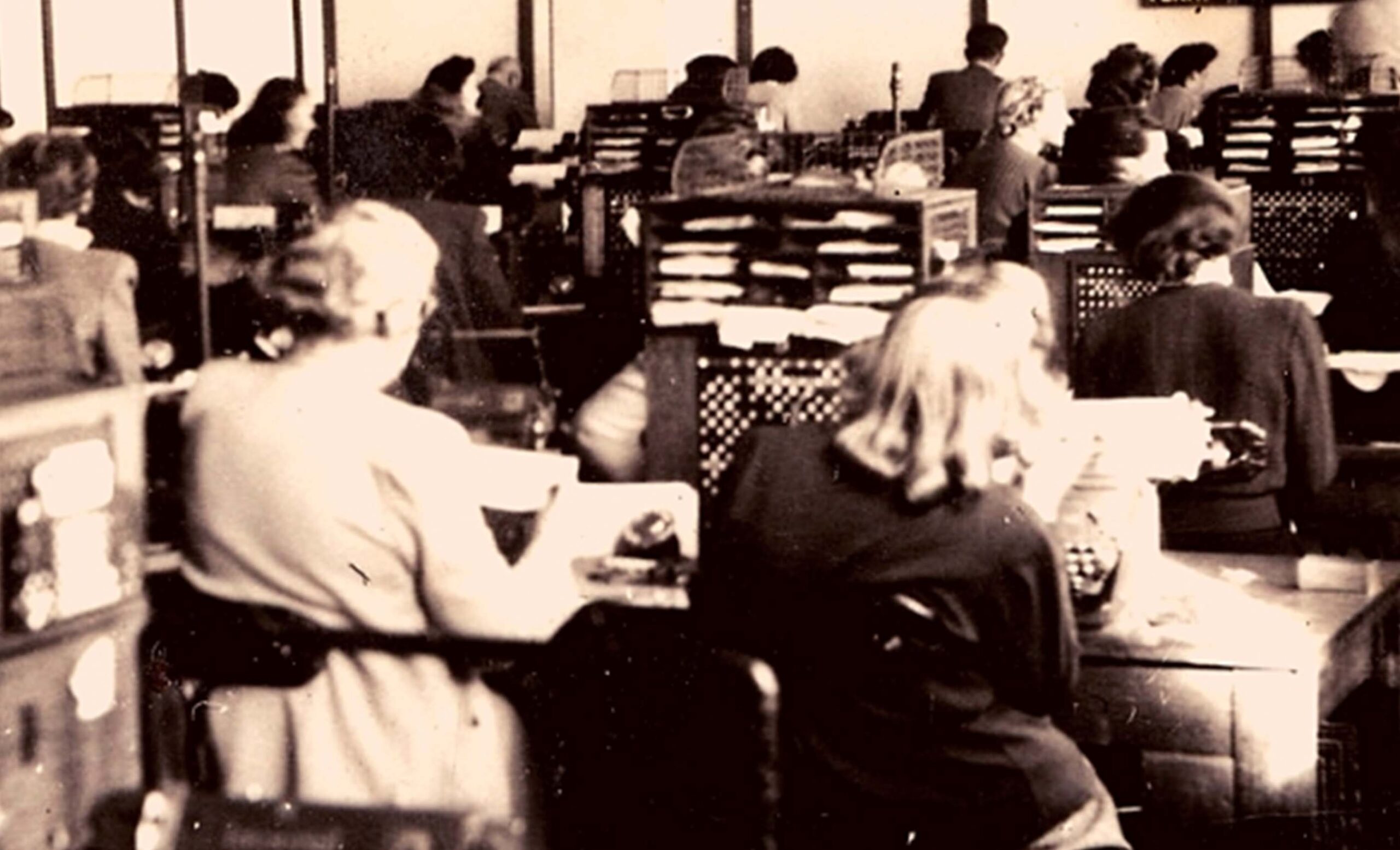 People sitting at desks typing in a newspaper office