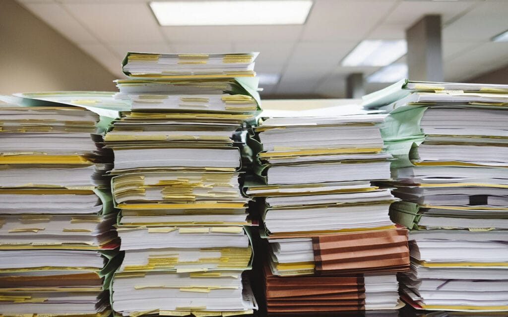 Organisational system represented by a stack of folders and papers with post-it notes.