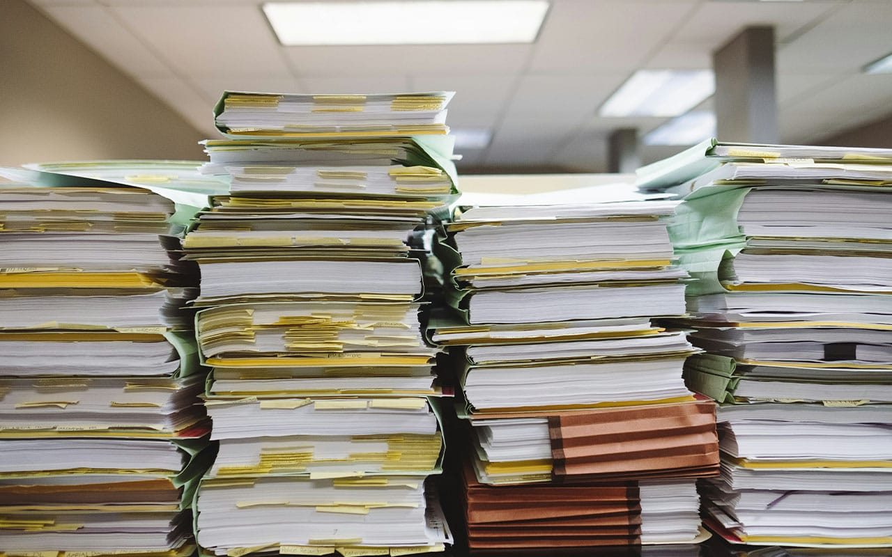 Organisational system represented by a stack of folders and papers with post-it notes.